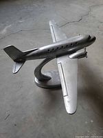 Three-quarter view of silver cast metal airplane on base