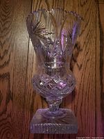 full view of vase front showing scalloped rim, starburst and diamond cuts, pedestal base