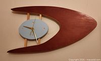 front view of atomic style wall clock showing boomerang frame, blue face, gold hands