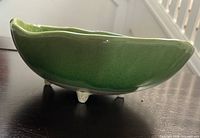 Side profile showing green glaze and four pedestal legs