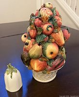 Fruit topiary and bell together on table for scale and context