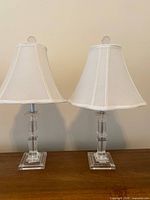 Pair of lucite lamps with shades on wooden surface