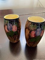 Front view of both vases showing fruit design and yellow interiors
