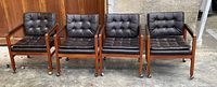 Front view of four matching brown tufted vinyl armchairs on casters