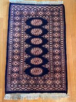 Full view of navy Bokhara rug showing overall design and fringe