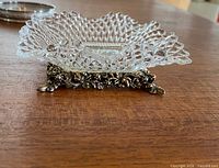 Side view showing pressed glass dish atop ornate metal stand