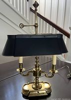Front view showing brass lamp, black tole shade, double arms, base