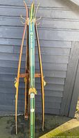 Front view of coat rack showing green Skilom ski, brass hooks and bindings