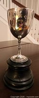 full view of silver goblet trophy on wood base