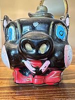 front view of ceramic pig jar showing painted facial details
