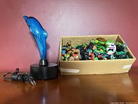 full lot showing dolphin lamp and cardboard box filled with action figures