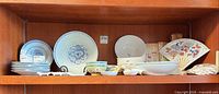 Full shelf view showing assortment of plates, bowls, chopstick rests, fan plates, disposable chopsticks