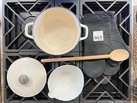 Top view of Dutch oven body, lid, ceramic bowl, wooden spoon, pair silicone mitts