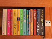 Row of 13 Jamie Oliver book spines on shelf