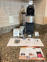 Full view of Keurig brewer with accessories and manuals on countertop