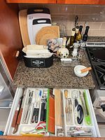 overall lot on counter: cutting boards, bread bin, bottles, mills, mortar & pestle, drawer of utensils