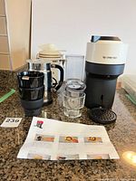 Group shot showing machine, frother, cups, canister, sugar shaker, accessories and manual