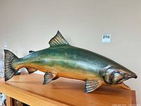 Left profile of painted wooden fish sculpture on shelf