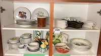 Cabinet view showing assorted plates, platters, jars, bowls, corn dishes and holders