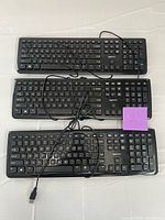 Three AmazonBasics black wired USB keyboards with cables displayed