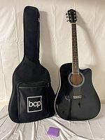 Guitar standing next to black soft gig bag