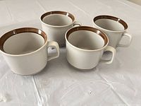Four stoneware cups angled to show exterior color, rims and handles