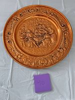 Full view of copper-plated wall plate on table showing overall design and size reference