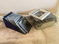 Floppy disk box beside purple CD holder filled with jewel cases