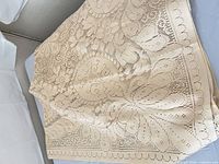 Folded beige crochet tablecloth showing overall colour and texture