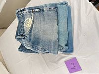 Two folded Levi’s jeans, one showing thigh tear