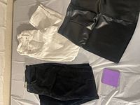 Overview of white jeans, black jeans, black faux leather skirt
