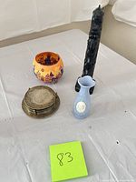 Group shot of all items: blue vase, brass coaster stack, orange glass votive, black totem