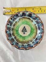 Top view showing tree motif, scalloped rim and tape measure indicating about 5 in diameter