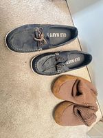 Pair of Old Navy boat shoes and brown slippers on carpet