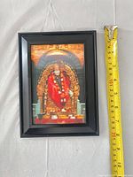 Front view showing framed Sai Baba print with measuring tape for scale