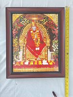 Front view of framed Sai Baba wall art with measuring tape showing approx 16 in height and 12 in width