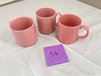Top and side view of three pink ceramic mugs together on table