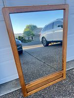 Full view of rectangular oak-framed mirror leaning against wall