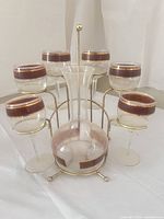 Full set showing decanter centered in gold-tone stand surrounded by six glasses