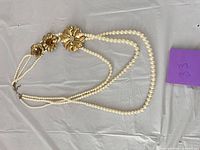 Full view of necklace showing four strands, flowers, clasp