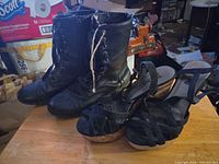 Pair of black ankle boots and pair of black wedge sandals on table