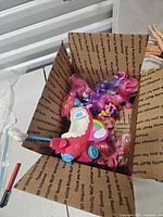 Open box showing multiple My Little Pony figures and pink carriage