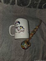 Mug with Cheshire Cat graphic beside hand-painted wooden pipe