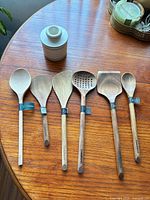 Group shot of six wooden utensils and ceramic butter pot