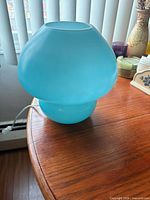 Full view of blue glass mushroom lamp on table