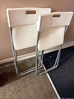 Front view of two white IKEA Gunde folding chairs leaned together