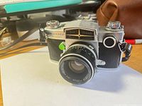 Front view of Miranda Sensorex camera with attached 50mm lens and leatherette case in background