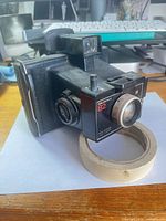 Front three-quarter view of Polaroid Colorpack 82 camera showing lens, shutter and flash socket