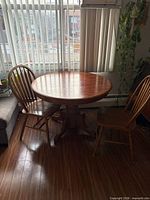 Round wooden table with two chairs in room