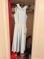 Full view of pale blue sleeveless dress hanging, showing overall style and length